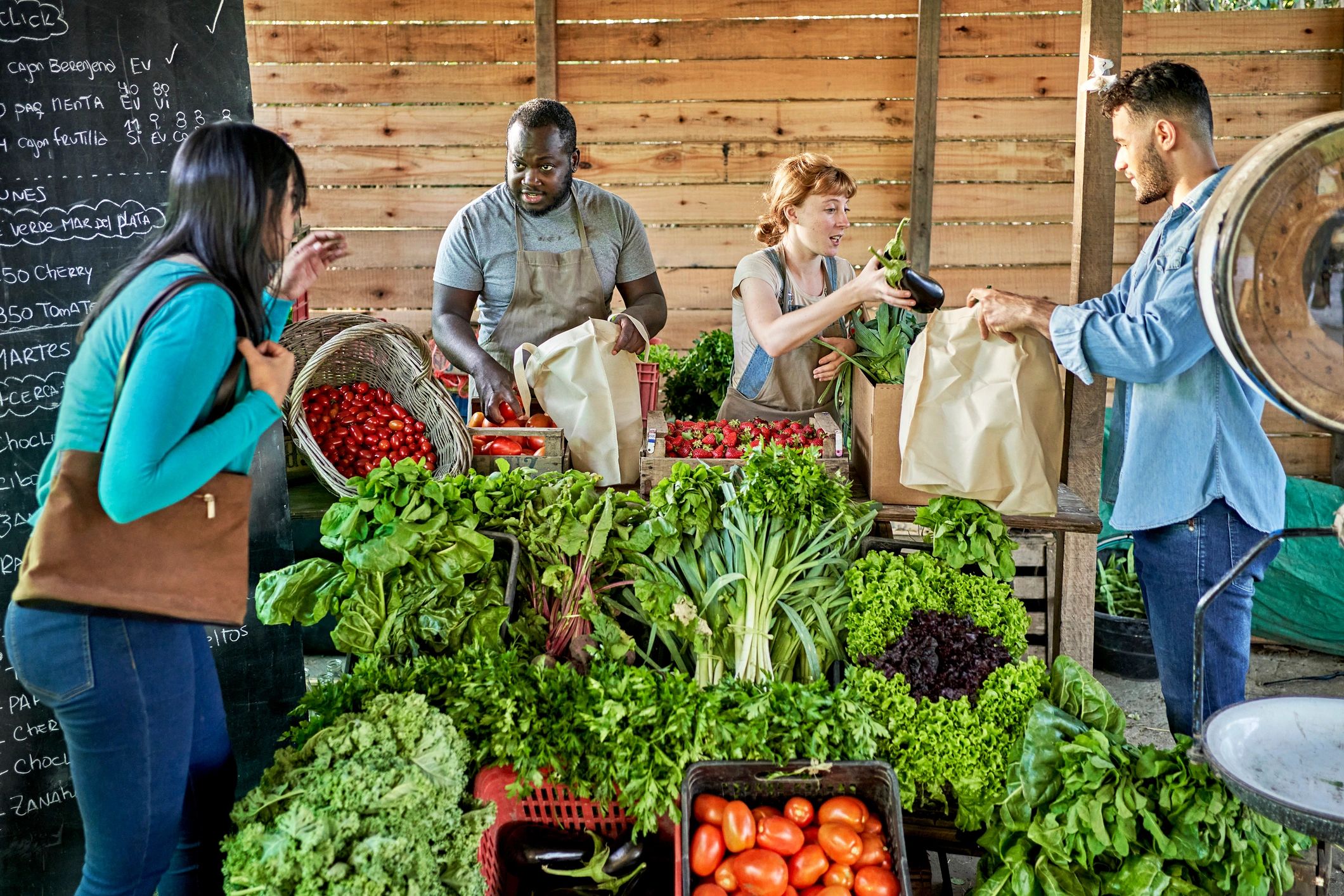 Customers buying fresh produce directly from farmers at a market stand