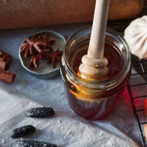 Raw Wildflower Honey — jar of honey with a wooden dipper and wildflowers in warm natural light